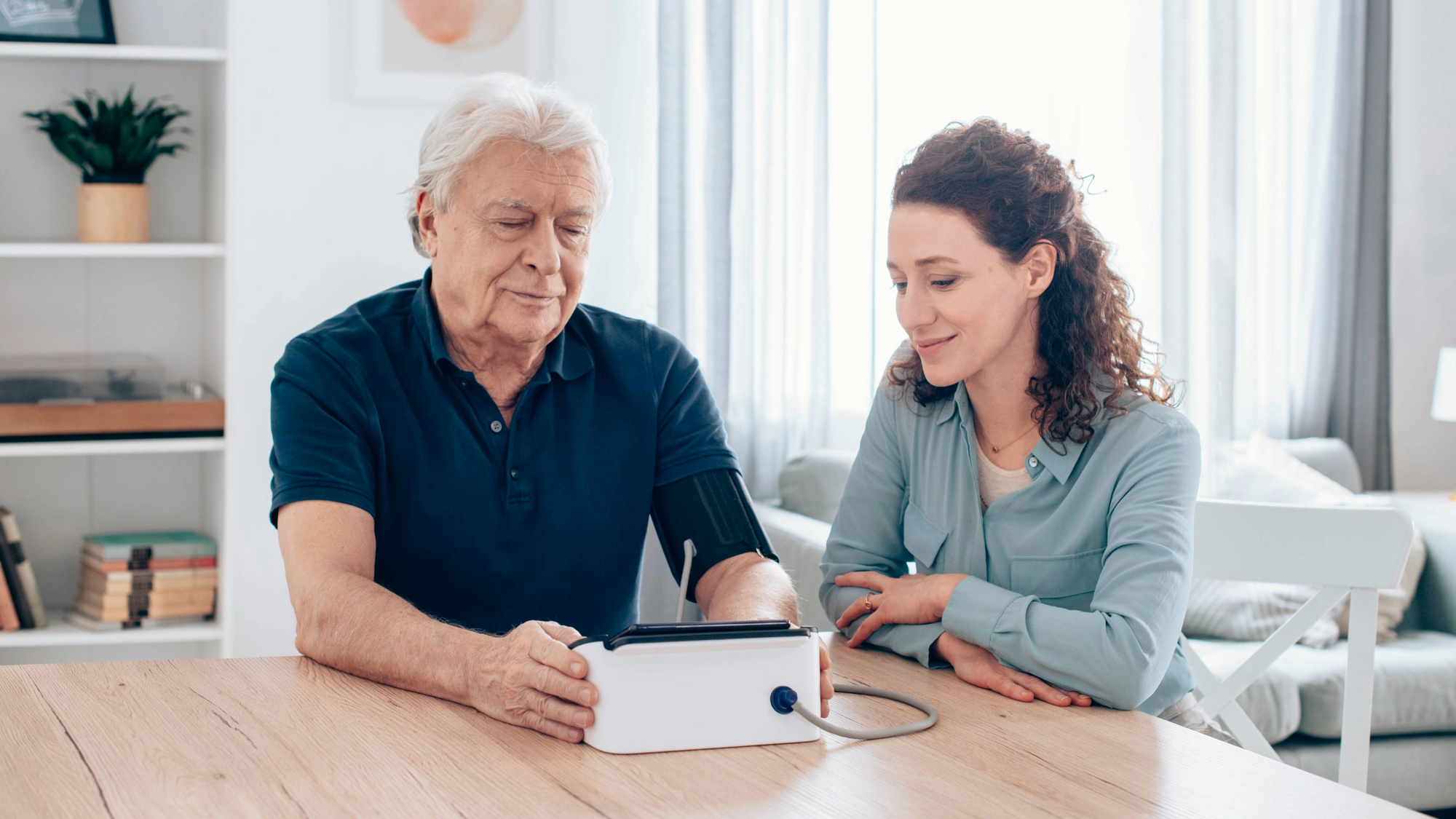 Terveys: Mies ja nainen pöydän ääressä mittaamassa verenpainetta Omron verenpainemittarilla