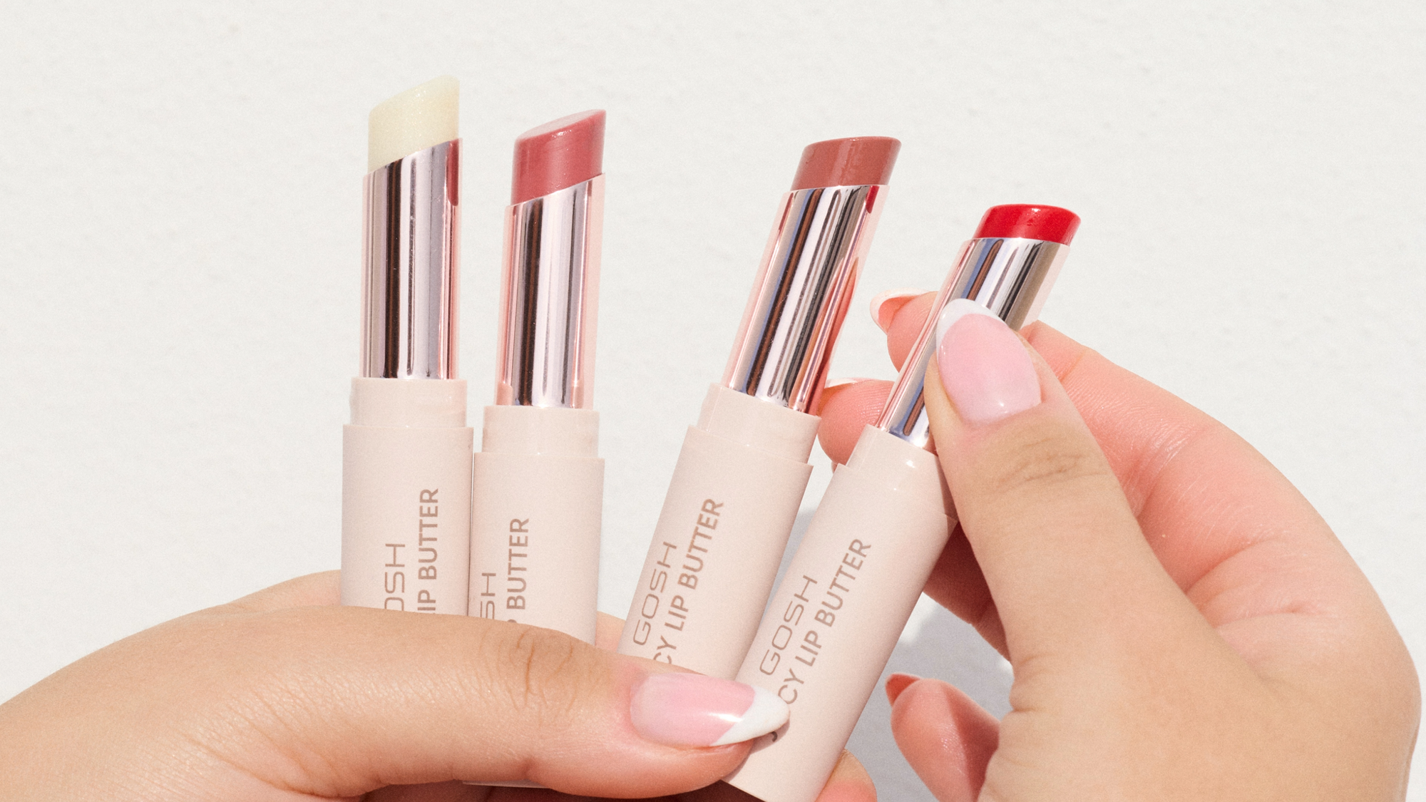 Huulimeikki: naisen punaiset huulet, joihin levitetään GOSH Lip Butter huulikiiltoa