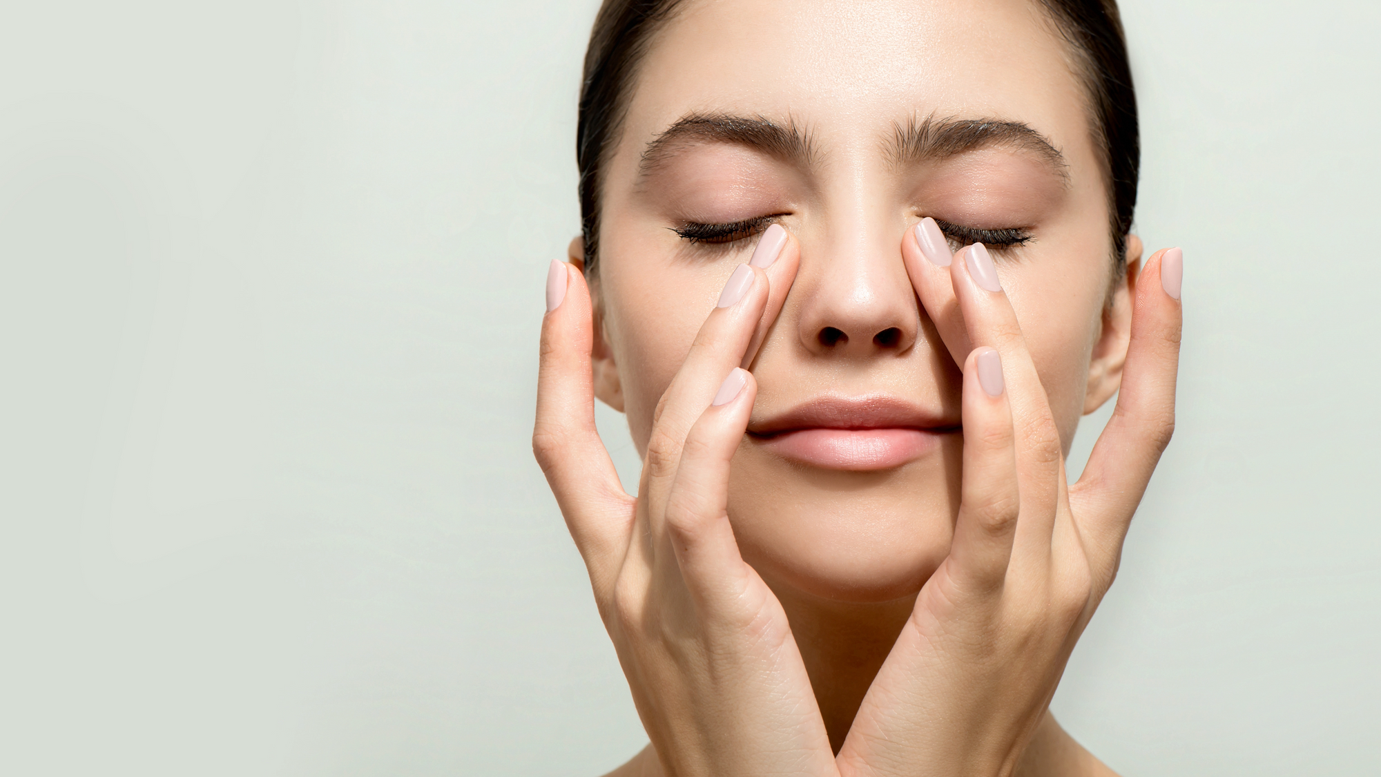 Nainen painelee silmänympärysihoaan sormillaan