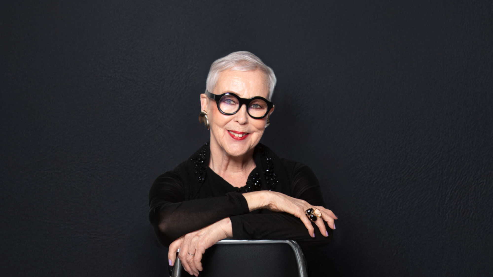 Raili Hulkkonen istuu tuolissa ja teksti onnea Raili 80 vuotta