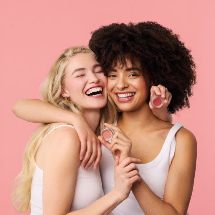 Kaksi nauravaa naista halailee ja pitää käsissään Murumuru poskipunia