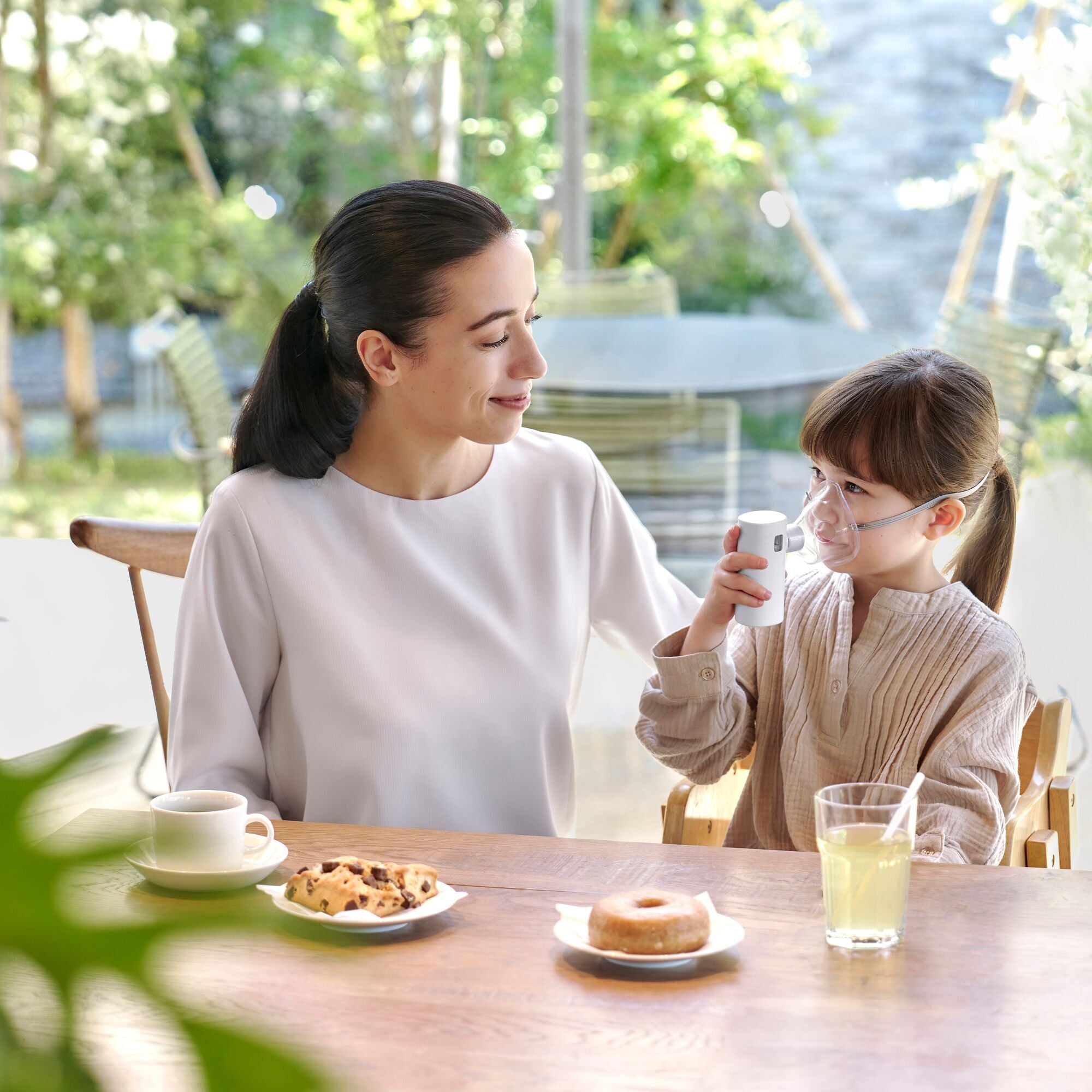 Äiti ja lapsi ruokapöydän ääressä lapsella käytössä Omron MicroAIR Go sumutin