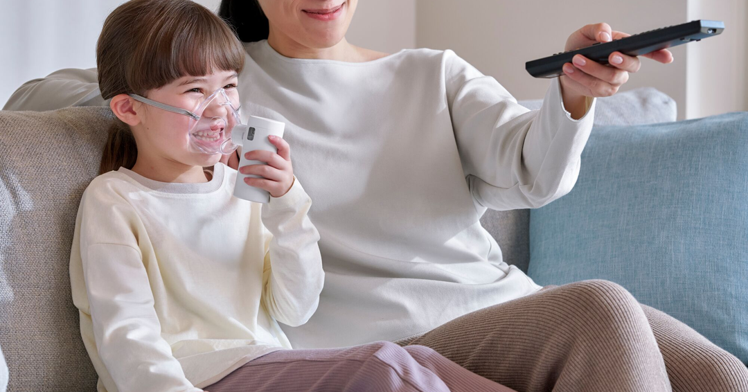 Omron MicroAir GO sumutin käytössä lapsella, joka istuu sohvalla