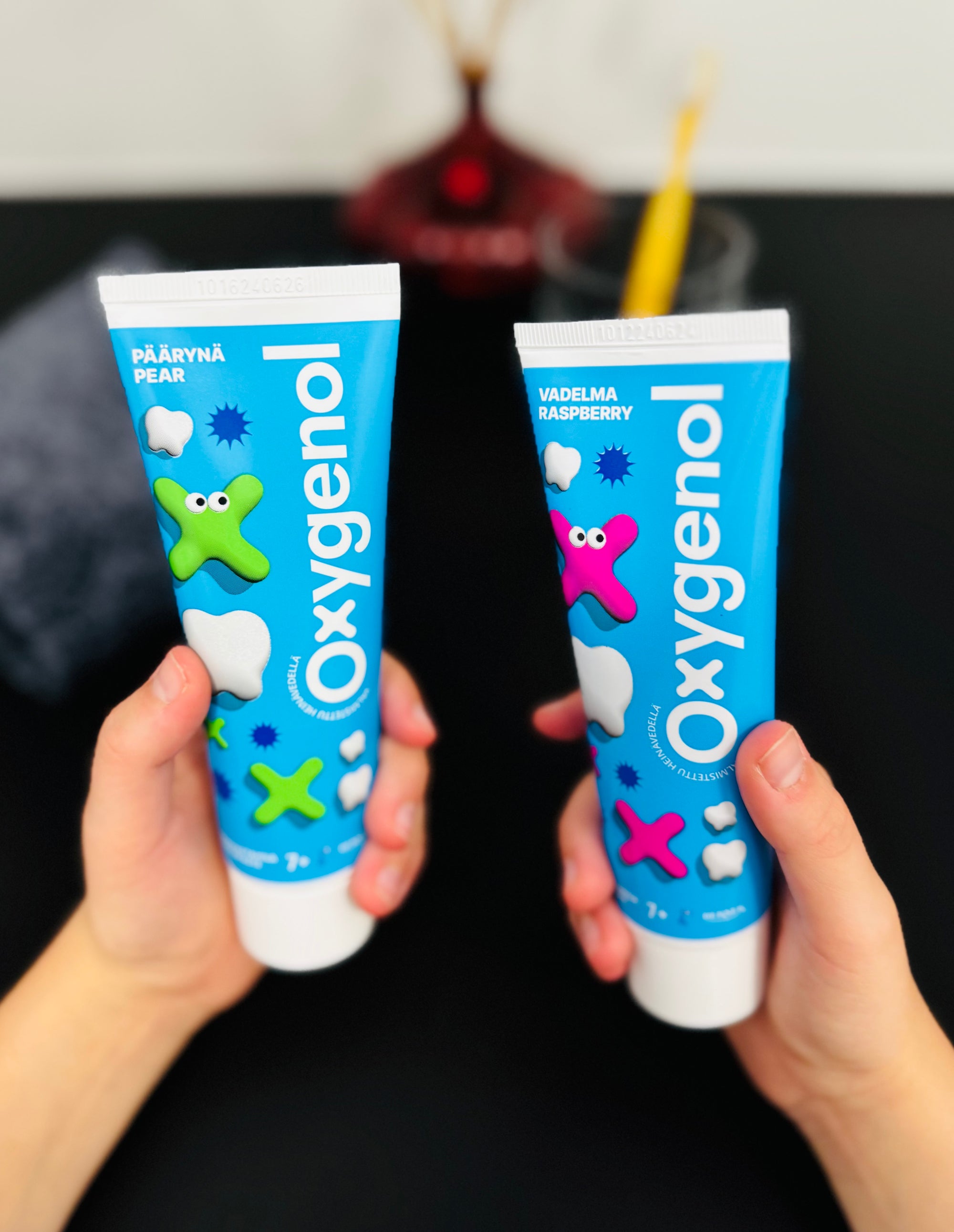 Oxygenol 7+ päärynä ja vadelma hammastahnat lapsen käsissä